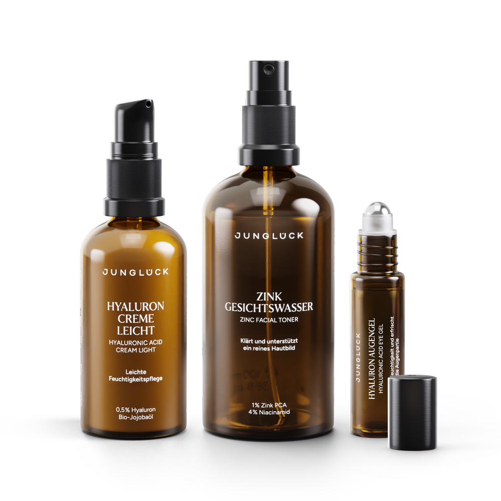 Drei Produkte von JUNGLÜCK: Eine Braunglasflasche mit Hyaluron Creme leicht, ein Zink Gesichtswasser und ein Hyaluron Öl.