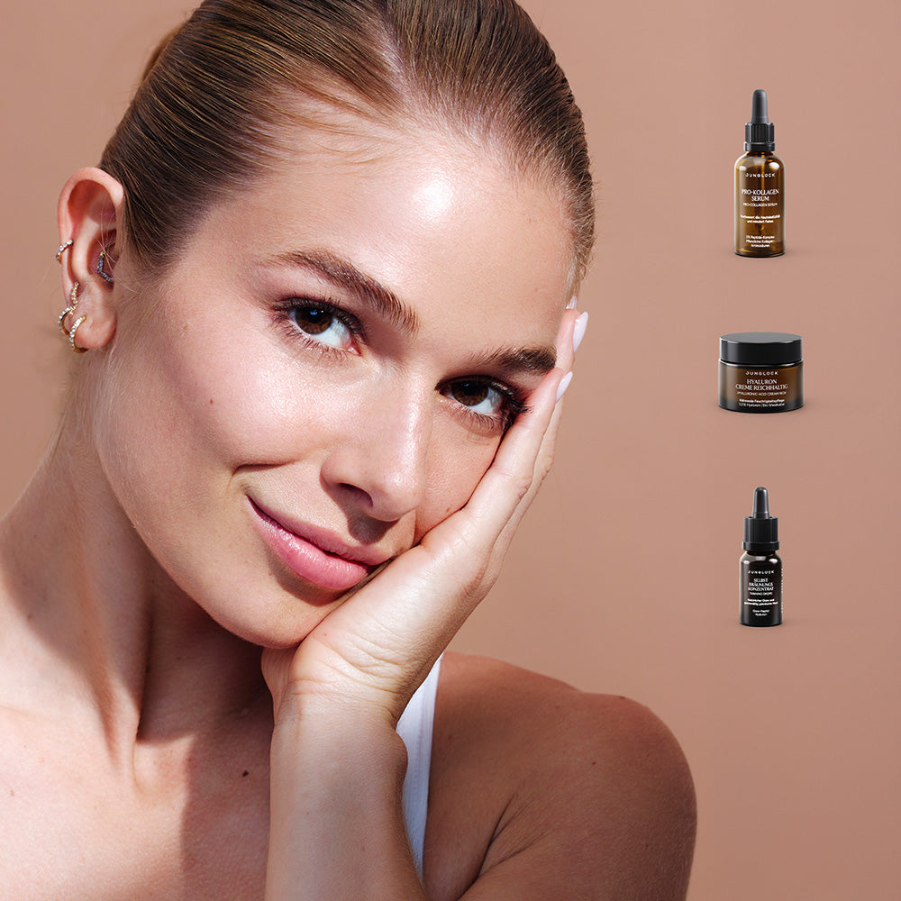 Eine junge Frau trägt ein leichtes Make-up und berührt sanft ihr Gesicht. Im Hintergrund sind drei Produkte aus dem Lolas