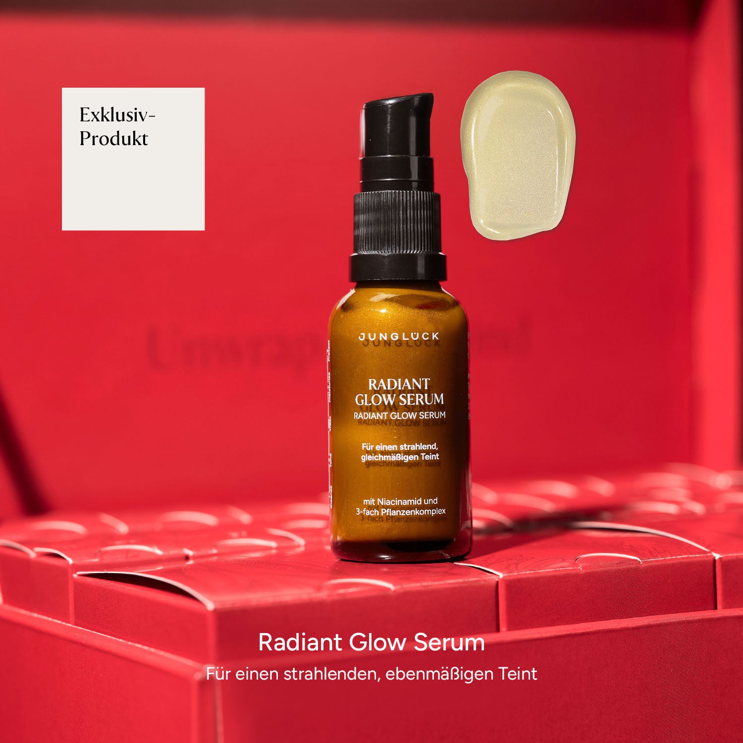 Braunglasflasche mit Radiant Glow Serum, daneben eine kleine Menge des Serums auf einem Untergrund. Roter Hintergrund.