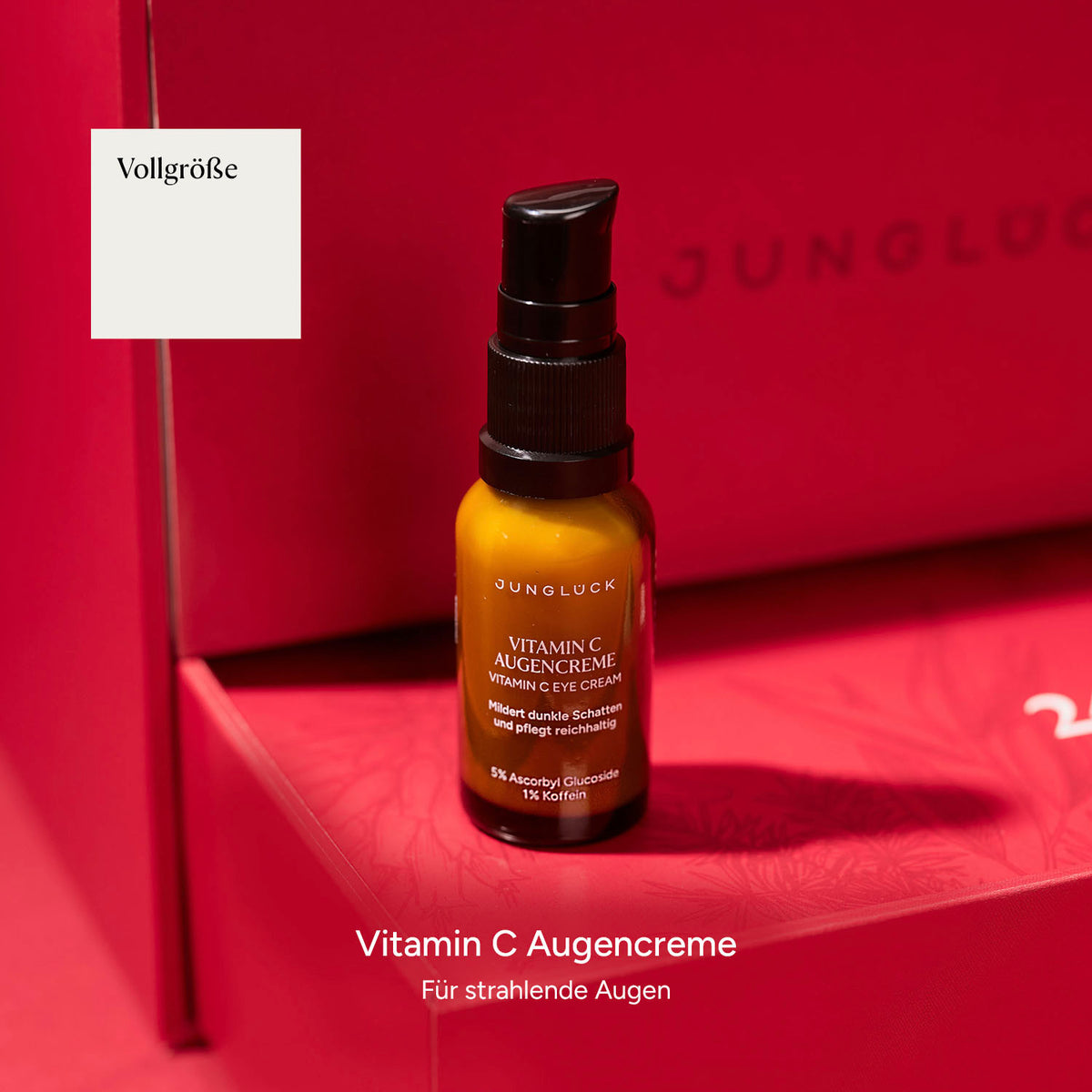 Braunglasflasche mit Vitamin C Augencreme auf pinkem Hintergrund. Text beschreibt die Anwendung und Inhaltsstoffe.