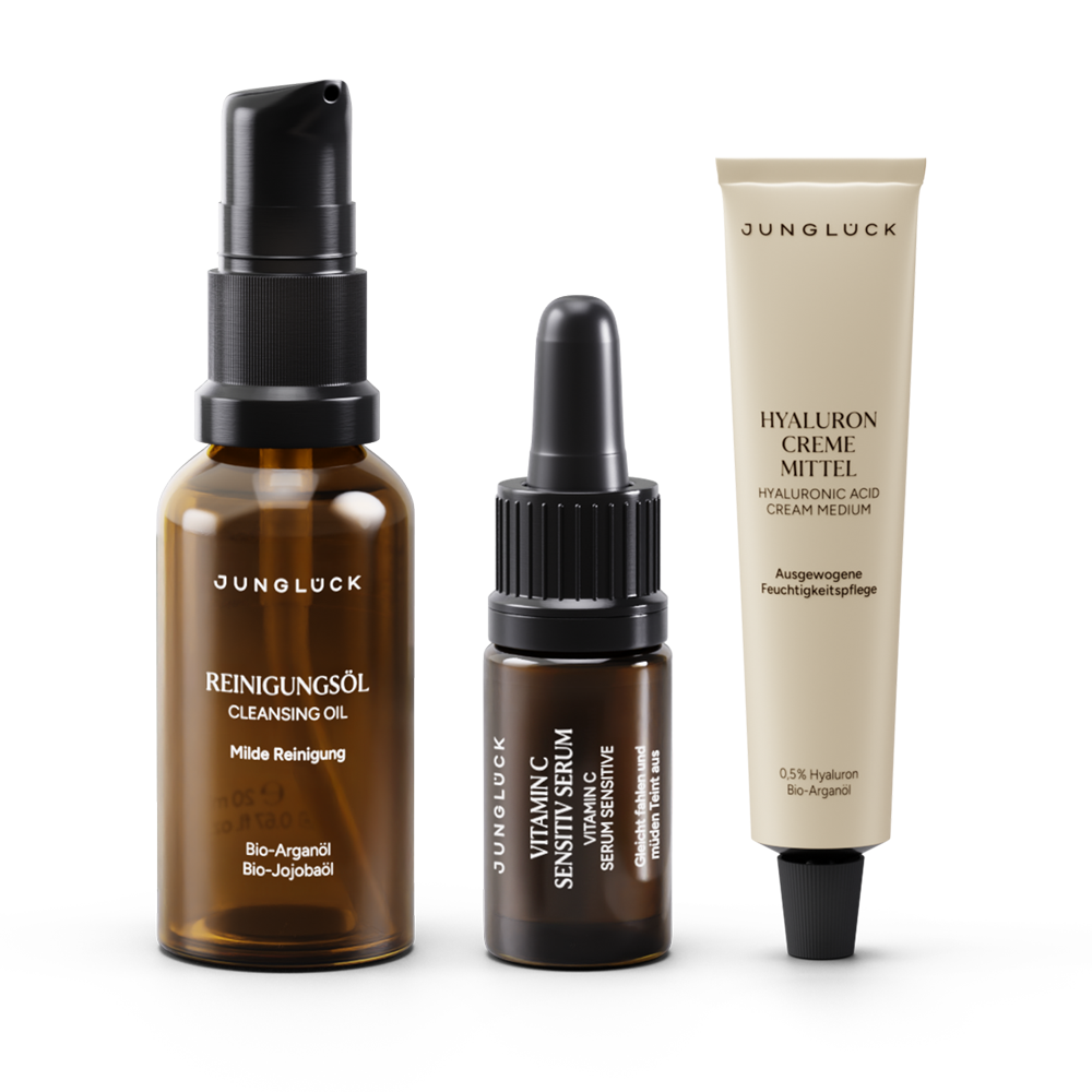 Drei JUNGLÜCK Produkte: Braunglasflasche mit Reinigungsöl, Pipettenflasche mit Vitamin Sensitiv Serum und Tube mit Hyaluron