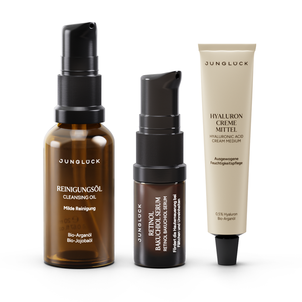 Drei Produkte aus dem JUNGLÜCK Glatt Strahlend Pflege Trio: ein mildes Reinigungsöl in einer Braunglasflasche, ein Serum in