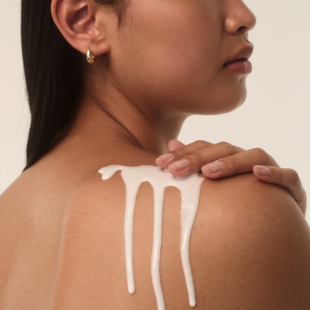 Nahaufnahme einer Schulter mit einer Creme, sanft aufgetragen. Weiche Textur, die die Haut umschmeichelt.