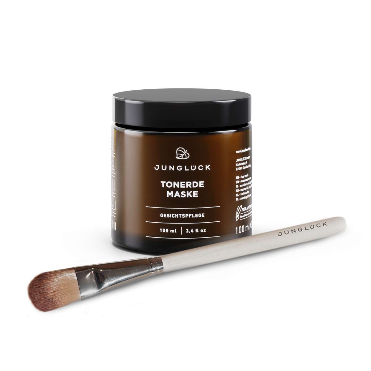 JUNGLÜCK Tonerde Maske in 100 ml Braunglasbehälter, begleitet von einem Pinsel zur Anwendung, auf hellem Hintergrund.